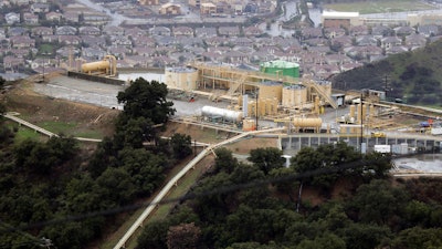 This Jan. 12, 2017, file photo shows gas gathering plant on a hilltop at the Southern California Gas Company's Aliso Canyon storage facility near the Porter Ranch neighborhood of Los Angeles. Attorneys for families sickened and forced from their Los Angeles homes after the nation's largest-known natural gas leak have reached a $1.8 billion settlement with the utility.