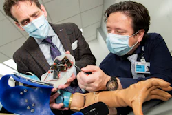 The research group in Cleveland Clinic's Laboratory for Bionic Integration looking at the inside of the touch robot system. Each small black box provides individual finger sensation to the user through a neural-machine interface.