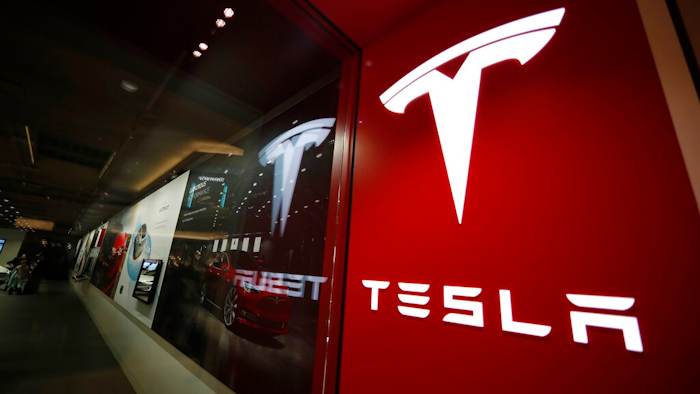 This Feb. 9, 2019, file photo shows a sign bearing the company logo outside a Tesla store in Cherry Creek Mall in Denver. Tesla says it delivered 241,300 electric vehicles in the third quarter in 2021, even as it wrestled with a global shortage of computer chips that has hit the entire auto industry. The Palo Alto, California, company’s sales from July through September beat Wall Street estimates.