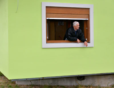 Vojin Kusic's stands on window of his rotating house in a town of Srbac, northern Bosnia, Sunday, Oct. 10, 2021.
