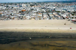 Workers in protective suits clean a contaminated beach in Newport Beach, Calif., Oct.6, 2021.