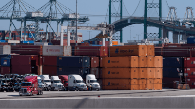 In this Tuesday, Oct. 19, 2021, photo trucks line up next to containers at the Port of Los Angeles in san Pedro, Calif.