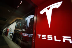This Feb. 9, 2019, file photo shows a sign bearing the company logo outside a Tesla store in Cherry Creek Mall in Denver. A driver was behind the wheel when a Tesla electric car crashed and burned last April in Houston, killing two men, neither of whom was found in the driver’s seat. The U.S. National Transportation Safety Board announced the findings in an investigative report released Thursday, Oct. 21, 2021 on the April 17 crash on a residential road in Spring, Texas.