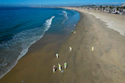 Workers clean oil from the sand south of the pier in Newport Beach, Calif., Tuesday, Oct. 5, 2021. A leak in an oil pipeline caused a spill off the coast of Southern California, sending about 126,000 gallons of oil into the ocean, some ending up on beaches in Orange County.