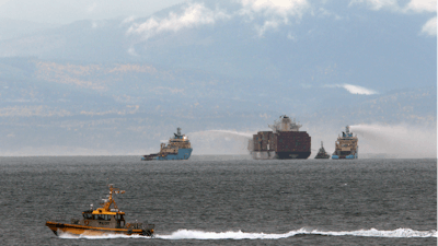 Ships work to control a fire onboard the MV Zim Kingston about 8 kilometers (5 miles) from the shore in Victoria, British Columbia, Canaeda, on Sunday, Oct. 24, 2021. The container ship caught fire on Saturday and 16 crew members were evacuated and brought to Ogden Point Pier.