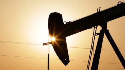 In this Wednesday, Sept. 30, 2015 file photo, an oil pump works at sunset in the desert oil fields of Sakhir, Bahrain. A U.N.-backed study has found that the world needs to cut by more than half its production of coal, oil and gas in the coming decade to maintain a chance of keeping global warming from reaching dangerous levels.