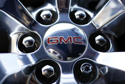 In this April 25, 2017 file, photo, a GMC logo is displayed on the wheel of a truck at a General Motors dealer's lot in Nashville, Tenn. General Motors plans to cash in as the world switches from combustion engines to battery power, promising to double its annual revenue by 2030 with an array of new electric vehicles, profitable gas-powered cars and trucks, and services such as an electronic driving system that can handle most tasks on the road.
