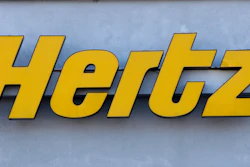 In this Tuesday, Nov. 28, 2017 photo a Hertz rental car logo rests on the front of a Hertz location, in Boston. Car rental company Hertz is ordering 100,000 electric vehicles from Tesla. The company says it’s buying the Tesla Model 3s by the end of 2022, and it also will buy electric vehicle chargers.