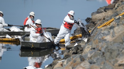 Cleanup contractors unload collected oil in plastic bags trying to stop further oil crude incursion into the Wetlands Talbert Marsh in Huntington Beach, Calif., Sunday, Oct. 3, 2021. One of the largest oil spills in recent Southern California history fouled popular beaches and killed wildlife while crews scrambled Sunday to contain the crude before it spread further into protected wetlands.