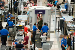 Travelers wear face coverings in the line for the south security checkpoint in the main terminal of Denver International Airport on Aug. 24, 2021, in Denver. The Biden administration is detailing its new international COVID-19 air travel polices, which will include exemptions for kids and new federal contact tracing requirements.