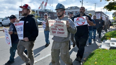 Justin Paetow, center, a tin shop worker at Bath Iron Works, takes part in a demonstration against COVID-19 vaccine mandate outside the shipyard on Friday, Oct. 22, 2021, in Bath, Maine.