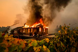 Vines surround a burning building as the Kincade Fire burns through the Jimtown community of unincorporated Sonoma County, Calif., on Oct. 24, 2019. Pacific Gas & Electric has reached a settlement agreement, Nov. 3, 2021, with state regulators over the 2019 Kincade fire, which was ignited by the utility's electrical transmission equipment in a remote area of Sonoma County.