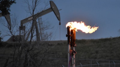 A flare to burn methane from oil production is seen on a well pad near Watford City, North Dakota, Aug. 26, 2021. A huge social and environmental policy bill passed by House Democrats includes a plan to impose a fee on emissions of methane, a powerful pollutant that leaks from oil and gas wells and contributes to global warming.