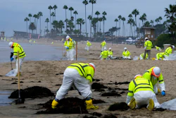 Workers in protective suits clean the contaminated beach in Corona Del Mar after an oil spill off the Southern California coast, on Oct. 7, 2021. A Los Angeles federal grand jury on Wednesday, Dec. 15 charged a Houston-based oil company and two subsidiaries for the oil spill off the California coast in October.