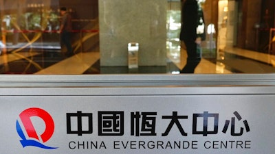 In this Oct. 4, 2021, file photo, a security guard stands at the headquarters of China Evergrande Group in Hong Kong. On Friday, Dec. 3, 2021, troubled Chinese developer China Evergrande Group, struggling under $310 billion in debt, warned it may run out of money to “perform its financial obligations,” sending regulators scrambling to reassure investors that China’s financial markets can be protected from a potential impact.