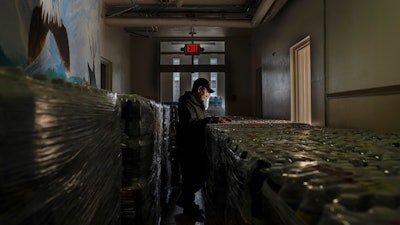 Dan Martinez, emergency manager for the Confederated Tribes of Warm Springs, pauses in the hallway of a storage building filled with donated water on Tuesday, Dec. 7, 2021, in Warm Springs, Ore. “The infrastructure bill brought joy to my heart because now it gives me hope — hope that it’s going to be repaired,” said Martinez, the tribes’ emergency manager.