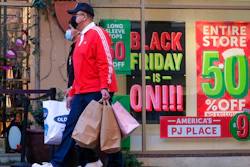Black Friday shoppers, wearing face masks, carry bags at the Citadel Outlets in Commerce, Calif., Friday, Nov. 26, 2021. Americans slowed their spending in November from October but they showed another month of resilience against higher prices and shortages in stores.