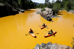 People kayak in water colored from a mine waste spill at the Animas River near Durango, Colo., Aug. 6, 2015.