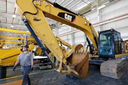 A Puckett Machinery Company technician walks past a new heavy duty Caterpillar excavator that awaits modification at Puckett Machinery Company in Flowood, Miss. Sept. 18, 2019. Caterpillar continued to see a healthy surge in sales during its fourth quarter of 2022, as the economy strengthens. Sales climbed 23% to $13.8 billion.