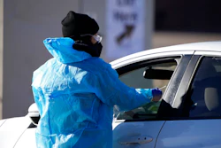 A medical technician performs a nasal swab test on a motorist queued up in a line at a COVID-19 testing site near All City Stadium Dec. 30, 2021, in southeast Denver. Millions of workers whose jobs don’t provide paid sick days are having to choose between their health and their paycheck as the omicron variant of COVID-19 rages across the nation. While many companies instituted more robust sick leave policies at the beginning of the pandemic, those have since been scaled back with the rollout of the vaccines, even though the omicron variant has managed to evade them.