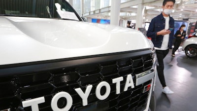 A man walks by the logo on a Toyota car at a showroom in Tokyo on Oct. 18, 2021. The shortage of parts caused by the coronavirus pandemic is further denting production at Toyota, Japan’s top automaker.
