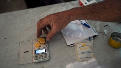 A gold miner weighs his weekly production at an illegal mine in the Amazon jungle, in the Itaituba area of Para state, Brazil, Aug. 22, 2020. Nuggets are spirited out of the jungle by prospectors to the nearest city where they are sold to financial brokers.