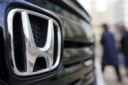 People walk near the logo of Honda Motor Company at a showroom Tuesday, Feb. 8, 2022, in Tokyo.