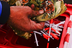 Keith Lewis disposes of used syringes at a needle exchange run by Camden Area Health Education Center in Camden, N.J., Thursday, Feb. 24, 2022. Four companies involved in the opioid industry are finalizing settlements over the addiction crisis in the U.S. in deals that could total $26 billion over 18 years.