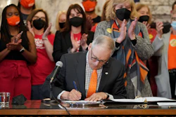 Washington Gov. Jay Inslee signs a bill that bans the manufacture, distribution and sale of firearm magazines that hold more than 10 rounds of ammunition at the Capitol in Olympia, March 23, 2022.