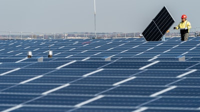 Electricians with IBEW Local 3 install solar panels on top of the Terminal B garage at LaGuardia Airport, Nov. 9, 2021, in the Queens borough of New York. The Commerce Department says it is investigating whether imports of solar panels from Southeast Asia are circumventing anti-dumping rules that block imports from China. The decision could dramatically reduce solar imports to the U.S. and undercut President Joe Biden’s ambitious climate goals. Clean energy leaders said the investigation could lead to thousands of layoffs in the domestic solar industry and imperil up to 80% of planned solar projects in the U.S.