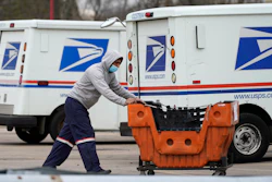A USPS employee works outside post office in Wheeling, Ill., Dec. 3, 2021. A government watchdog said says the U.S. Postal Service's environmental evaluation used for purchases of next-generation delivery vehicles relied on some false assumptions. Jill Naamane from the Government Accountability Office told the House Oversight Committee on Tuesday that the analysis used to determine the mix of gas- and electric-vehicles overstated maintenance costs of electric vehicles and relied on gas prices that don’t reflect the current reality.