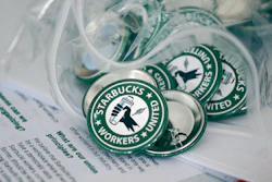 Pro-union pins on a table during a watch party for Starbucks' employees union election, Dec. 9, 2021, Buffalo, N.Y.