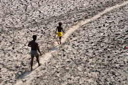 A man and a boy walk across the almost dried up bed of river Yamuna following hot weather in New Delhi, India, Monday, May 2, 2022. According to a report released by the World Meteorological Organization on Monday, May 9, 2022, the world is creeping closer to the warming threshold international agreements are trying to prevent, with nearly a 50-50 chance that Earth will temporarily hit that temperature mark within the next five years.