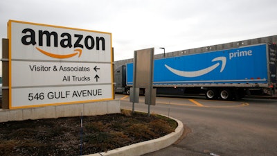 An Amazon Prime truck passes by a sign outside an Amazon fulfillment center March 19, 2020 in Staten Island, N.Y. The National Labor Relations Board has found merit to a complaint that Amazon violated labor law in New York City’s Staten Island by holding mandatory worker meetings to persuade its employees not to unionize. The agency’s determination was shared Friday, May 6, 2022 with an attorney representing the Amazon Labor Union, which filed the charge in the lead-up to the first successful U.S. organizing effort in the retail giant’s history.