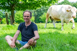 Ulf Allhoff-Cramer, farmer, sits in a pasture next to one of his cows in Detmold, Germany, Wedenesday, May 18, 2022. The organic farmer holds the VW car company partly responsible for damage to his farm. Together with Greenpeace, he wants to go to court to get VW to stop producing combustion vehicles by 2030.