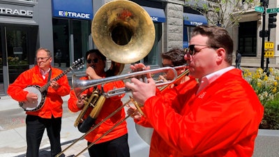Dan Gabel, right, and fellow musicians perform in downtown Boston, Tuesday, May 10, 2022. Gabel has canceled Netflix and other streaming services and tried to cut back on driving as the costs of gas, food, and other items, such as the lubricants he uses for his instruments, has soared. In the photo, from left to right, are Eric Baldwin, banjo; Ed Goroza, sousaphone; Josiah Reibstein, trombone; and Gabel, trumpet.