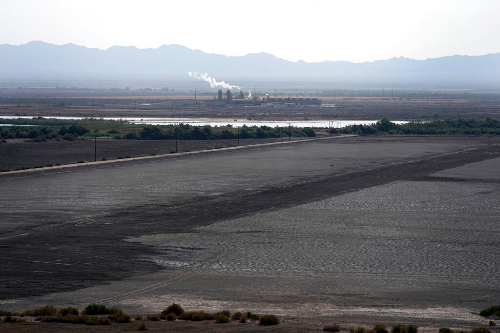 A dried up portion of the Salton Sea stretches out with a geothermal power plant in the distance in Niland, Calif., Thursday, July 15, 2021. Demand for electric vehicles has shifted investments into high gear to extract lithium from geothermal wastewater around the rapidly shrinking body of water. The ultralight metal is critical to rechargeable batteries.