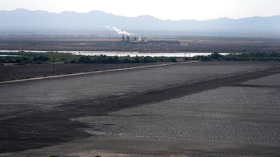 A dried up portion of the Salton Sea stretches out with a geothermal power plant in the distance in Niland, Calif., Thursday, July 15, 2021. Demand for electric vehicles has shifted investments into high gear to extract lithium from geothermal wastewater around the rapidly shrinking body of water. The ultralight metal is critical to rechargeable batteries.