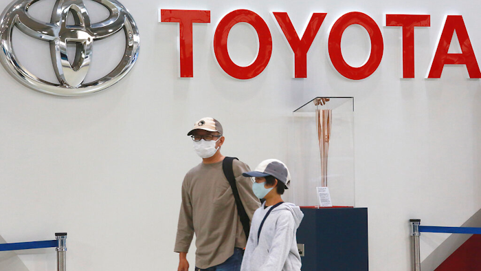 People walk past the logo of Toyota at a showroom in Tokyo Monday, Oct. 18, 2021. Toyota's profit declined 31% in the January-March 2022 quarter from the year before, but the Japanese automaker still wrapped up a year of record earnings.