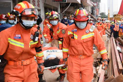 In this photo released by Xinhua News Agency, rescuers evacuate a woman pulled alive from a collapsed building in Changsha, central China's Hunan Province, May 1, 2022. The woman was rescued Sunday from the rubble of a building in central China more than 50 hours after it collapsed, leaving dozens trapped or missing, state media said.