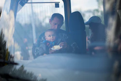 A man feeds a child as they arrive by bus at a reception center for displaced people in Zaporizhzhia, Ukraine, Monday, May 2, 2022. Thousands of Ukrainian continue to leave Russian occupied areas.