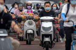 Commuters wearing face masks ride across an intersection in the central business district in Beijing, Friday, June 17, 2022.