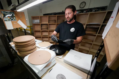 Ricky Riehl inspects finished vinyl records for physical flaws before they are packaged at the United Record Pressing facility Thursday, June 23, 2022, in Nashville, Tenn.