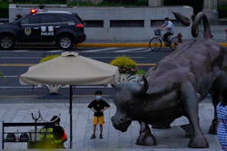 A child poses for a photo near a sculpture of a bull along the bund as day breaks, Wednesday, June 1, 2022, in Shanghai. Shanghai authorities say they will take major steps Wednesday toward reopening China's largest city after a two-month COVID-19 lockdown that has set back the national economy and largely confined millions of people to their homes.