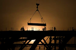 Workers are silhouetted against a sunset as they handle a steel frame on the roof of the Workers' Stadium under construction in Beijing, China, Monday, Feb. 28, 2022. China, the world’s top emitter of carbon dioxide and other greenhouse gases that cause global warming, has seen a notable dip in its carbon emissions over the past three quarters, as of June 1, 2022 — but it’s not clear how long the drop will continue.