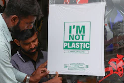 Workers paste degradable plastic substitute material on glass, Hyderabad, India, June 30, 2022.