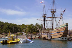 Brett Phaneuf, co-director of the Mayflower Autonomous Ship project, at left, stands on the deck of a tow boat as the Mayflower Autonomous Ship is guided next to the replica of the original Mayflower, Thursday, June 30, 2022, in Plymouth, Mass. The crewless robotic boat retraced the 1620 sea voyage of the Mayflower.