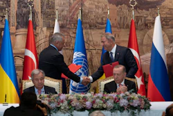 Turkish President Recep Tayyip Erdogan, right, and U.N. Secretary General, Antonio Guterres, sit as two representatives of Ukraine and Russia delegations check hands during a signing ceremony at Dolmabahce Palace, Istanbul, July 22, 2022.