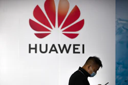 A man wearing a face mask walks past a billboard advertising Chinese technology firm Huawei at the PT Expo in Beijing, Oct. 14, 2020. Chinese tech giant Huawei said Friday, Aug. 12, 2022 its revenue fell in the first half of 2022 but new ventures in autos and other industries helped to offset a decline in smartphone sales under U.S. sanctions.