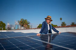 In this image provided by Ben Gibbs, Wendy Schmidt visits a community solar installation atop the roof of an Esperanza Community Housing apartment building, across the street from an oil drilling site in South Central Los Angeles on Nov. 3, 2021. The Schmidt Family Foundation funded the installation of the solar panels in 2017 so tenants could directly access renewable energy.